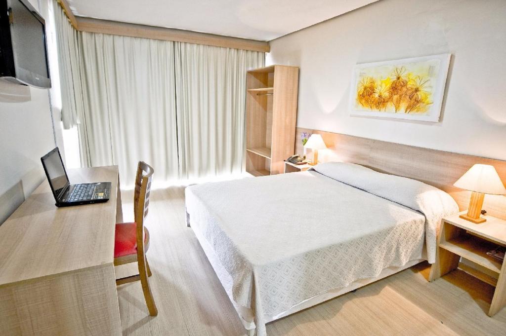 um quarto de hotel com uma cama, uma secretária e um computador portátil em Hotel Dan Inn Express Porto Alegre - 200 metros do Complexo Hospitalar Santa Casa e UFRGS em Porto Alegre