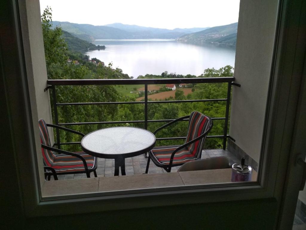 a balcony with a table and chairs and a view of a lake at Apartment Cats in Donji Milanovac