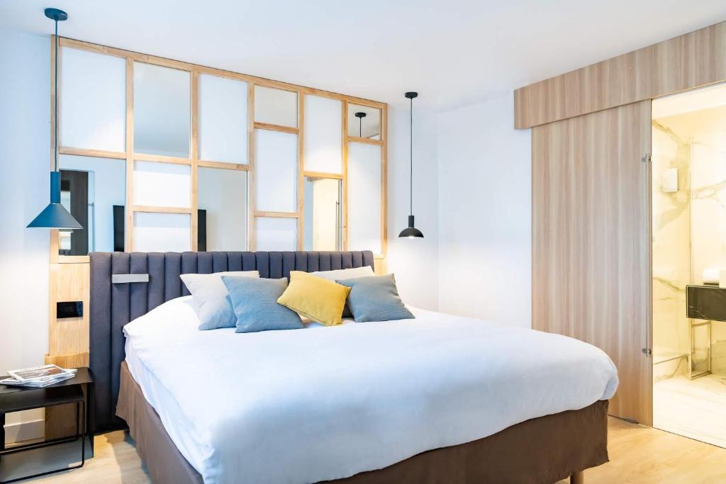 - une chambre dotée d'un grand lit avec des oreillers bleus et jaunes dans l'établissement Campanile PRIME - Suresnes - La Défense, à Suresnes