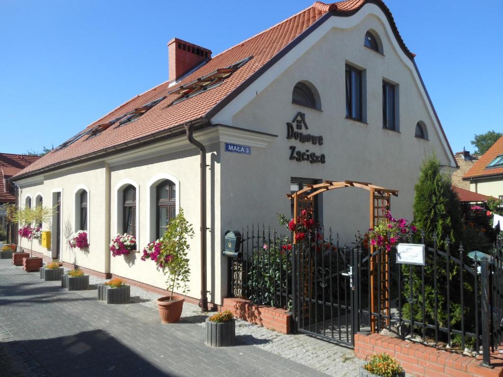 a white building with a black fence and flowers at Domowe Zacisze in Ustka