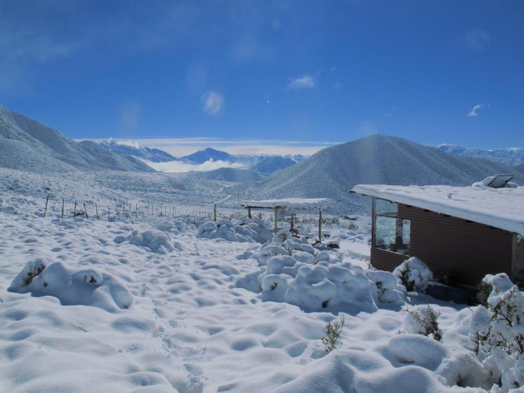 una casa cubierta de nieve con montañas en el fondo en La Ramada - refugio en Potrerillos