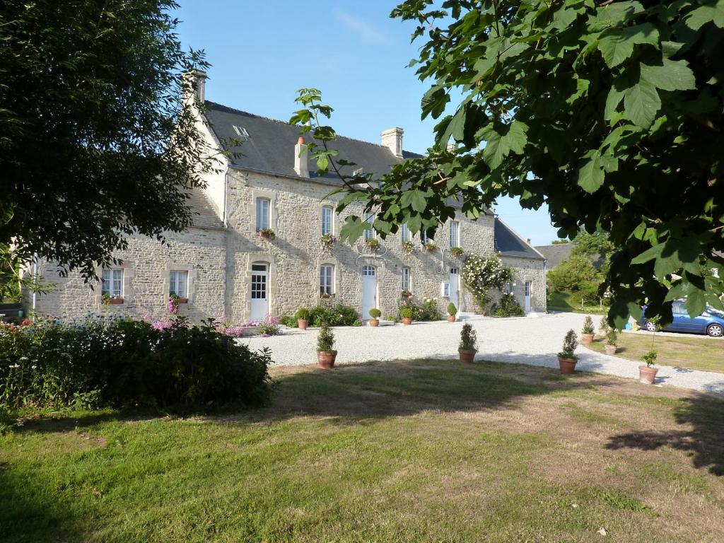 un gran edificio de piedra con un patio delante en Ferme du Loucel en Colleville-sur-Mer
