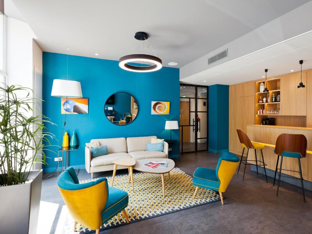 a living room with blue walls and yellow chairs at Hotel Des Remparts Perrache in Lyon