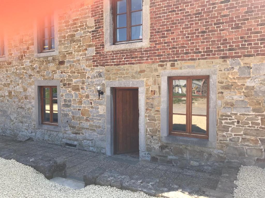 ein Backsteingebäude mit einer Tür und zwei Fenstern in der Unterkunft Le charme de l’Estroit in Mettet