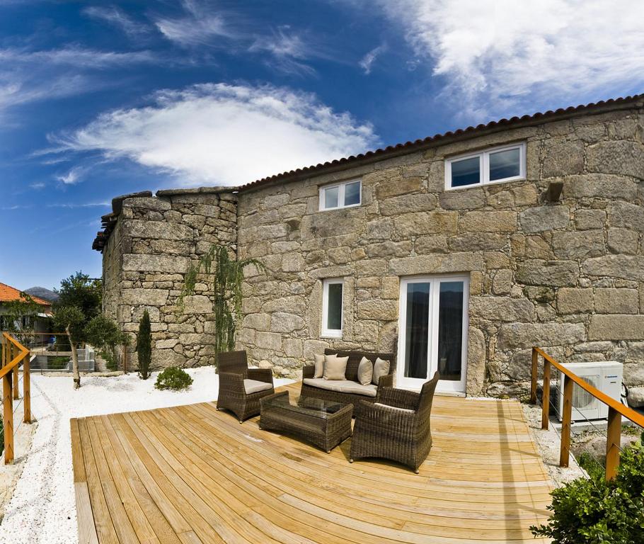 una terraza de madera con muebles frente a un edificio de piedra en RH Casas de Campo Design, en Parada