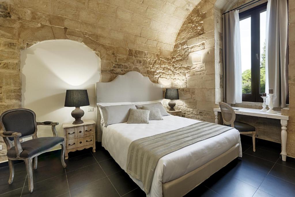 a bedroom with a bed and two chairs and a window at Itria Palace in Ragusa