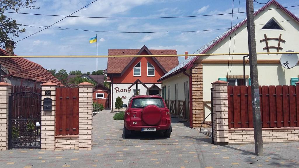 un pequeño coche rojo estacionado frente a una casa en Rand en Fontanka