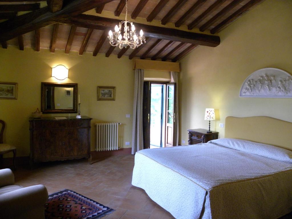 sypialnia z łóżkiem, telewizorem i żyrandolem w obiekcie Torraccia di Chiusi Agriturismo Relais w mieście San Gimignano