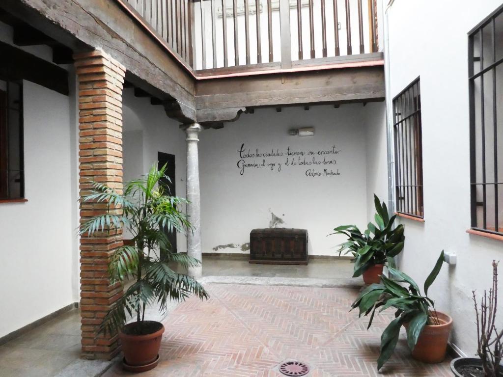 a courtyard with plants and a bench in a building at Apartamentos Nahira Suites 3000 in Granada