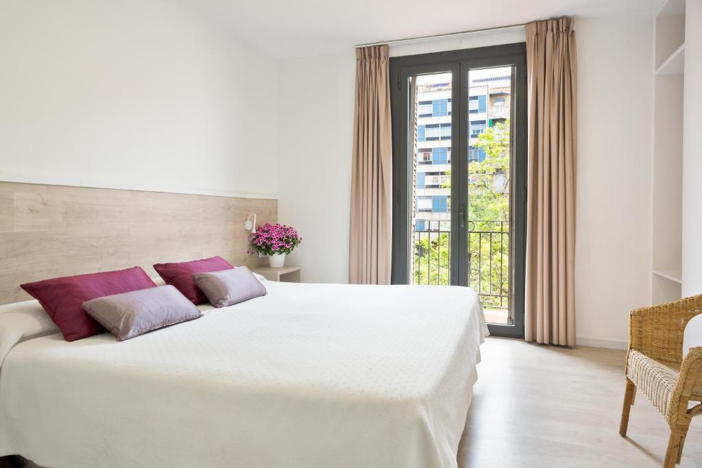 a bedroom with a large white bed with purple pillows at BcnStop Parc Güell in Barcelona
