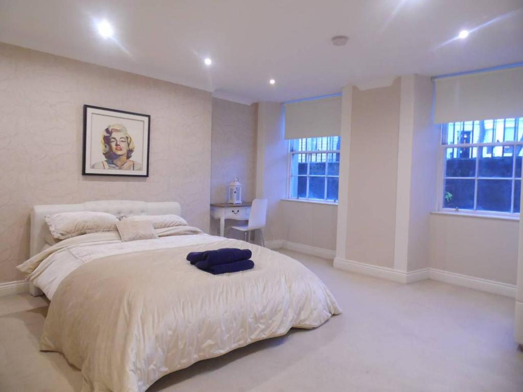 a white bedroom with a large bed and two windows at WEST END -Stunning, 2 bedroom, main door flat with private parking in Glasgow