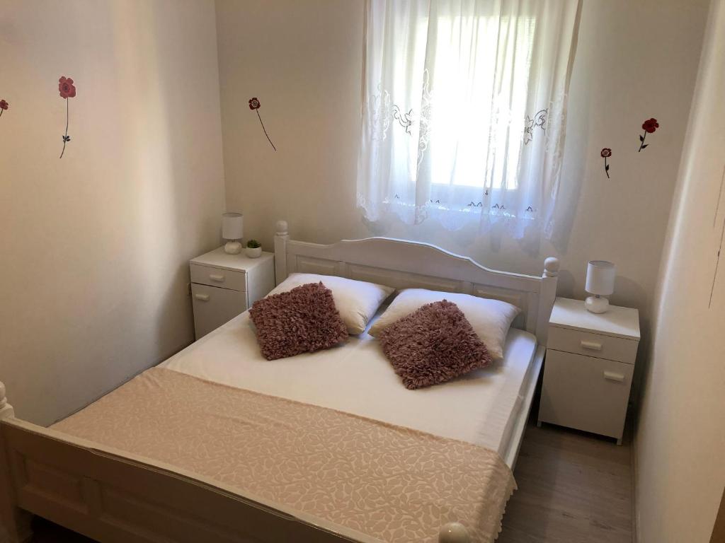 1 dormitorio con 1 cama con 2 almohadas y ventana en Apartments Vrdoljak, en Pag