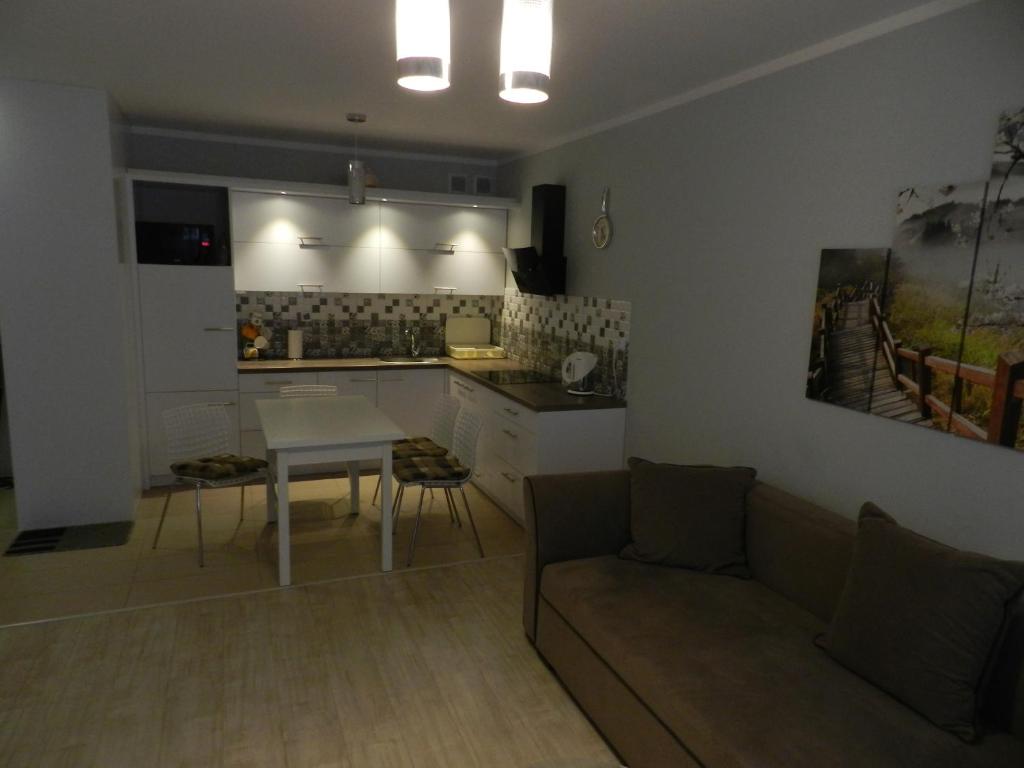 a kitchen and a living room with a couch and a table at Apartament całoroczny Bliżej Morza in Kołobrzeg