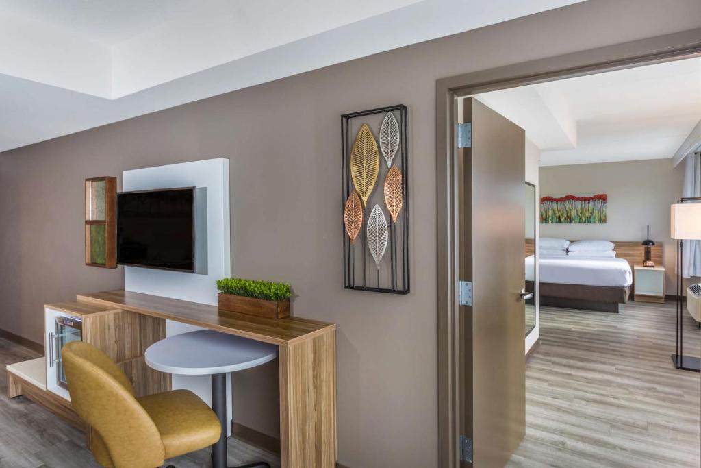 a living room with a television and a bedroom at Wyndham Garden Ft Lauderdale Airport & Cruise Port in Dania Beach
