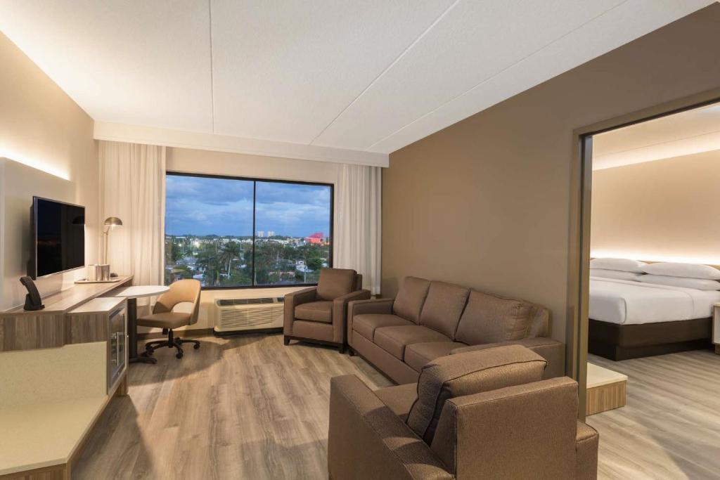 a hotel room with a couch and a bed at Wyndham Garden Ft Lauderdale Airport & Cruise Port in Dania Beach