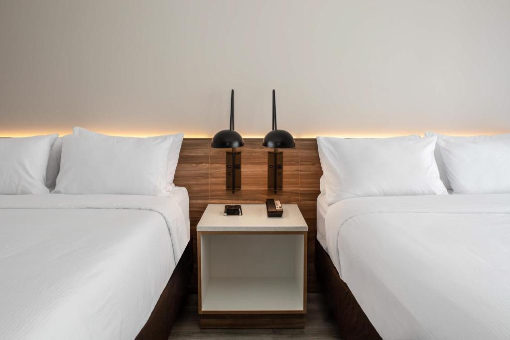 two beds sitting next to each other with a table at Wyndham Garden Ft Lauderdale Airport & Cruise Port in Dania Beach