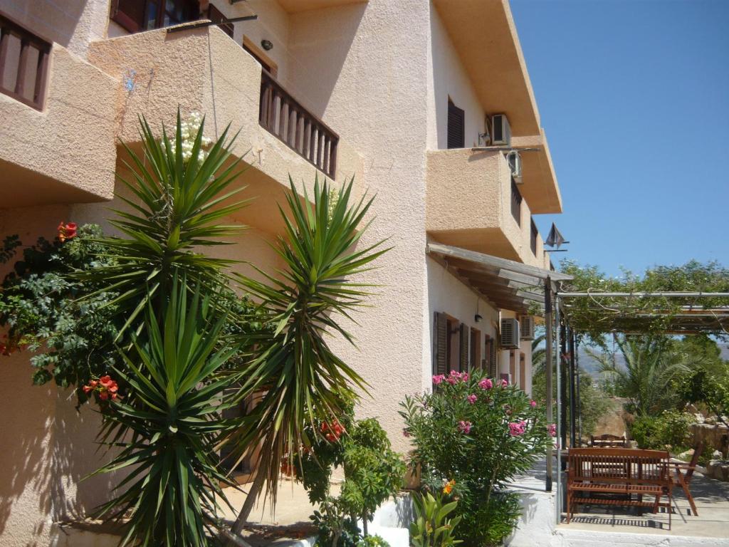 a building with palm trees and plants in front of it at Villa Victoria in Makry Gialos