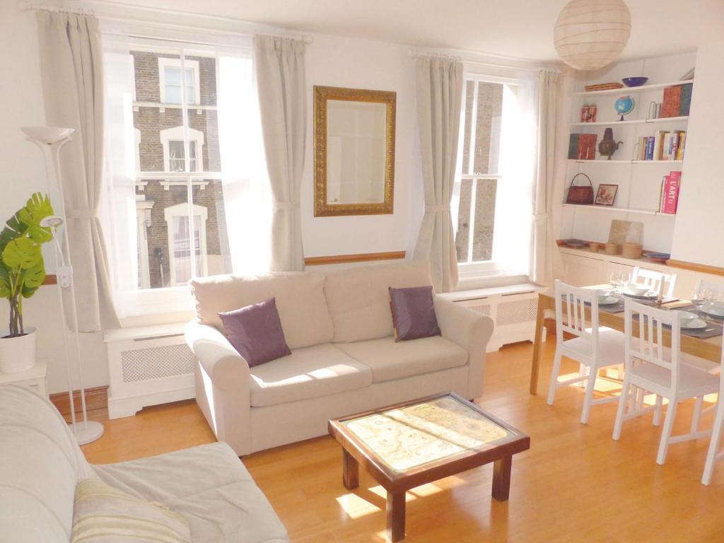 a living room with a white couch and a table at Bright, spacious 2 bedroom flat by Russell Square in London