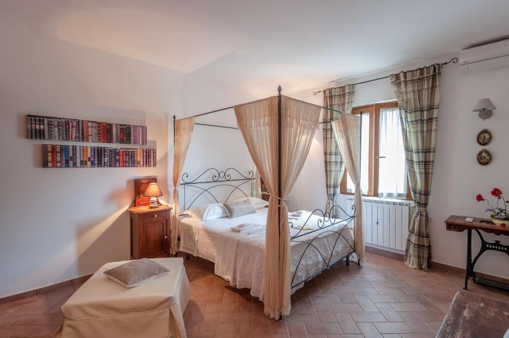 a bedroom with a canopy bed and a table at Le Tartarughe B&B in Magliano in Toscana
