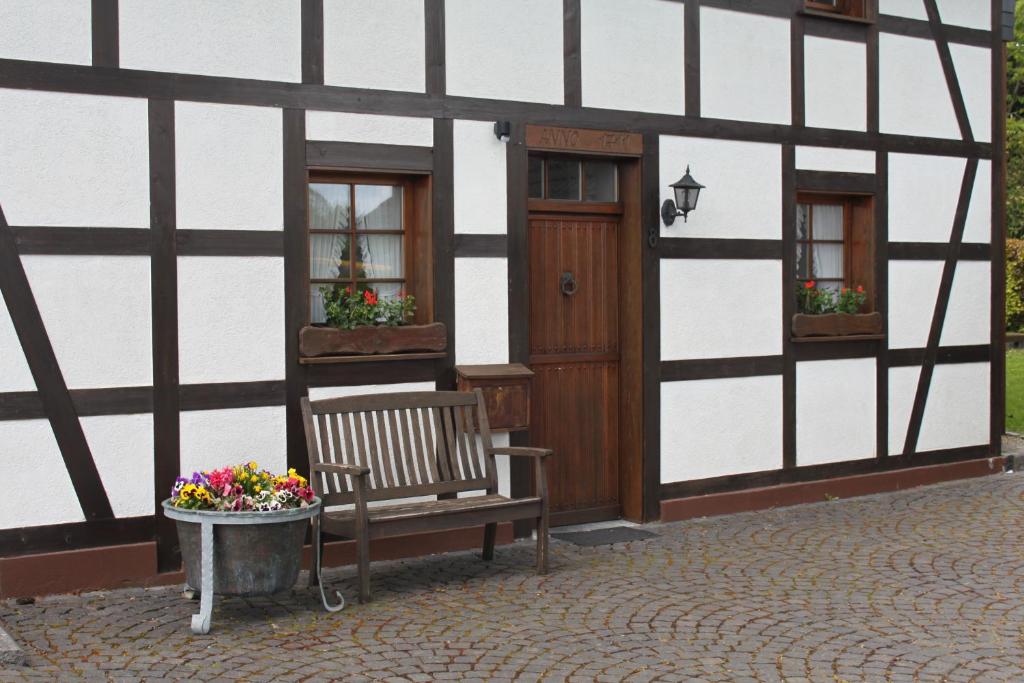 um banco sentado fora de um edifício com flores em um vaso em Ferienwohnung Haus Stein em Monschau