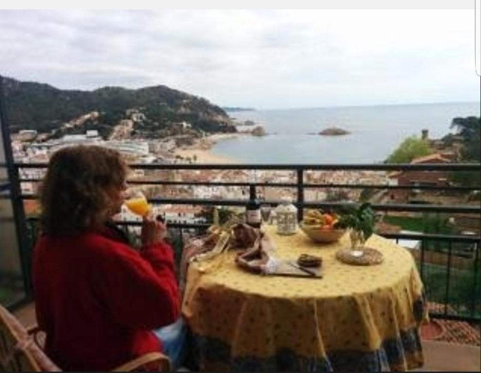a woman sitting at a table with a view of the ocean at PARADIS TOSSA in Tossa de Mar