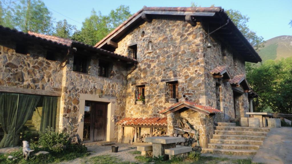 una antigua casa de piedra con escaleras y porche en Caseria la Infiesta, en Caleao