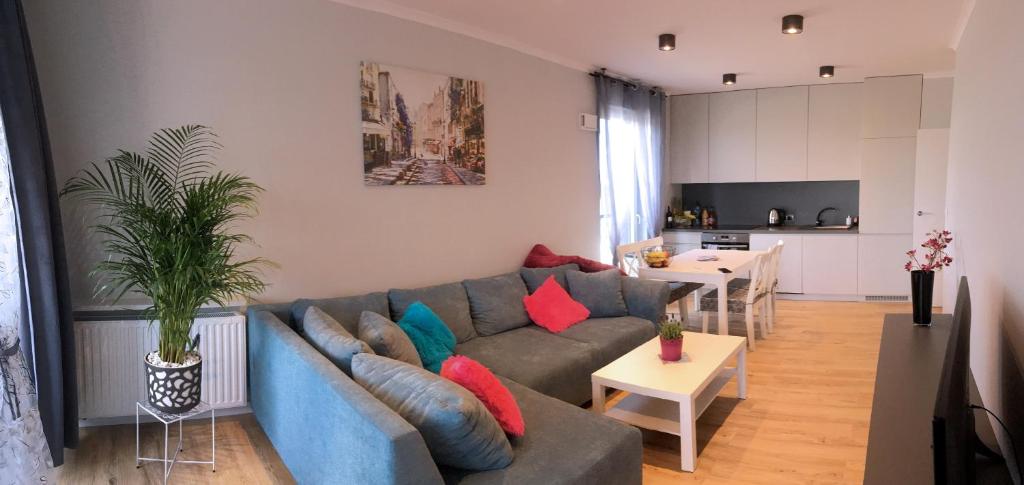 salon z niebieską kanapą i kuchnią w obiekcie APARTAMENT LIPSKA 4 w Krakowie