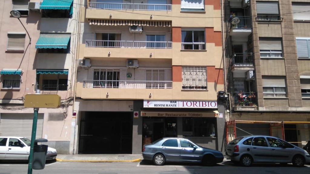 バレンシアにあるBig & Clean Apartmentの高層ビルの前に停車した車2台