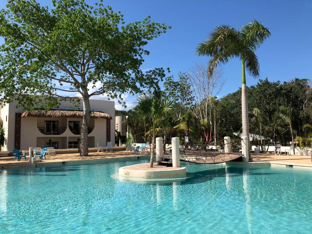 a large swimming pool with palm trees and a building at Casa Kaoba Hotel & Suites in Playa del Carmen