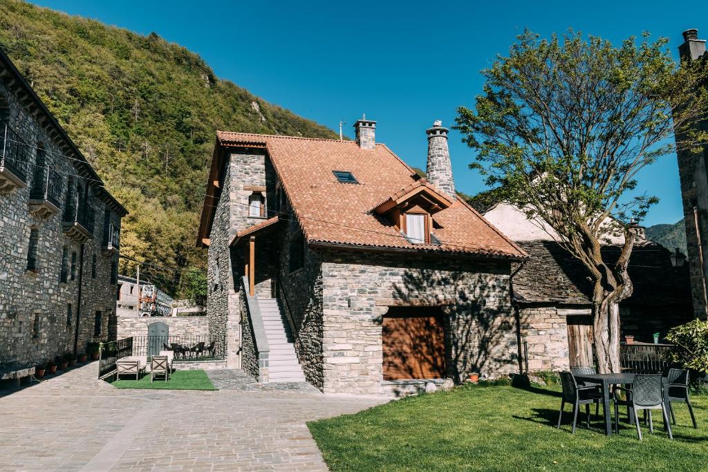 uma antiga casa de pedra com um telhado vermelho em Casa Rural Monte Perdido em Sarvisé