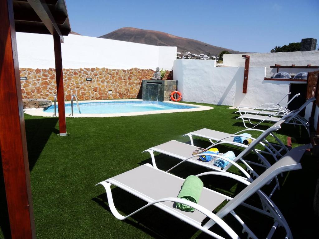 a group of lawn chairs sitting next to a swimming pool at Casita Joli in La Asomada
