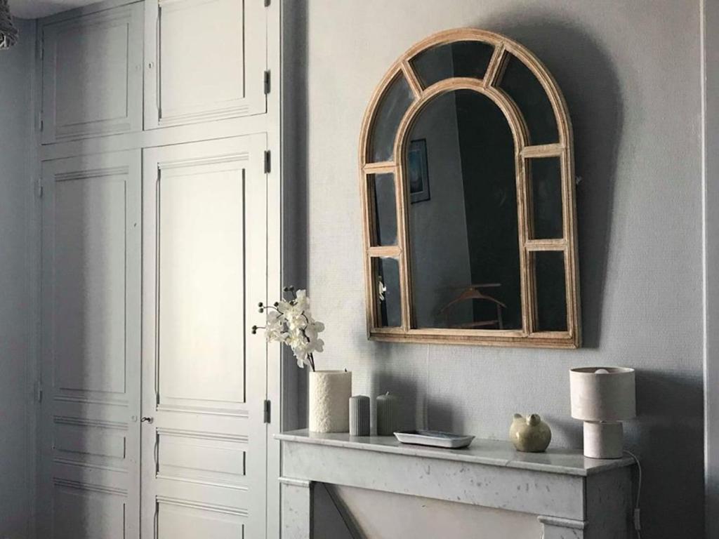 un espejo sentado en una pared junto a una chimenea en Le Compostelle Chic, Charme, Confort, Cocooning 80 m² en Saint-Léonard-de-Noblat