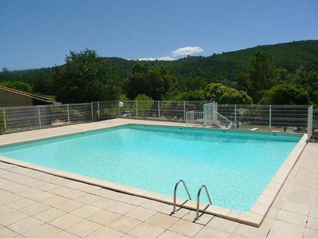 una gran piscina azul con una montaña en el fondo en Mazet de vacances dans le Domaine de l'Espaï, en Saint-Martin-de-Brômes