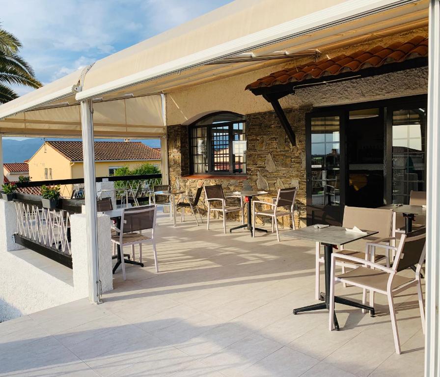 a patio with tables and chairs under a pavilion at Hôtel Le Belvedere in Saint-Cyprien
