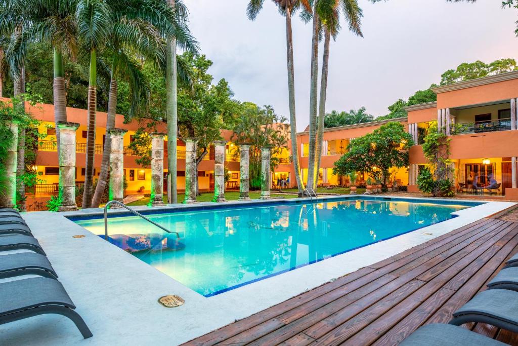 een zwembad voor een gebouw met palmbomen bij Hacienda Uxmal Plantation & Museum in Uxmal
