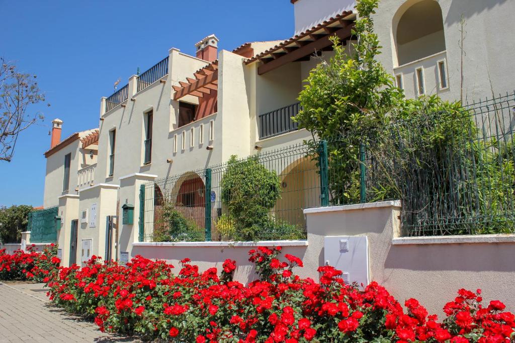 una fila de casas con flores rojas delante de ellas en (ROU002) Cómoda Casa con Puerta a la Piscina, en Ayamonte
