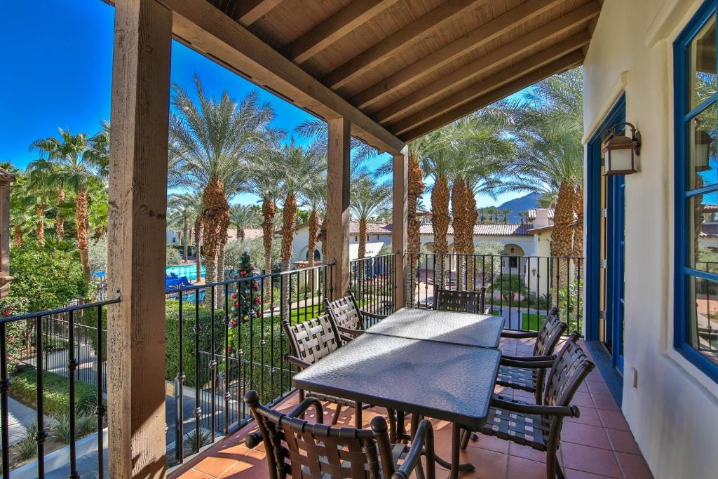a patio with a table and chairs and palm trees at L48 Premier Location At Clubhouse Condo in La Quinta