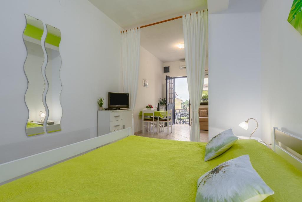 a bedroom with a green bed and a living room at Studio Apartments Romina in Vrsar