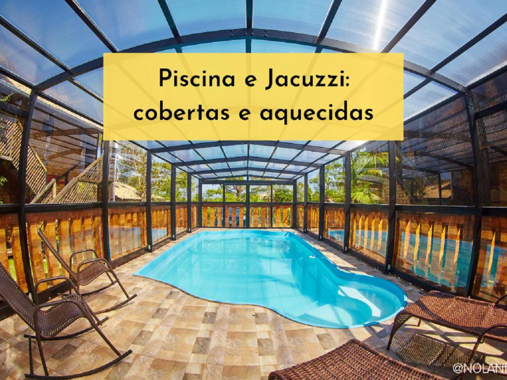 ein Schwimmbad in einem Glashaus mit einem Schild darüber in der Unterkunft Hotel Praia Do Rosa in Praia do Rosa