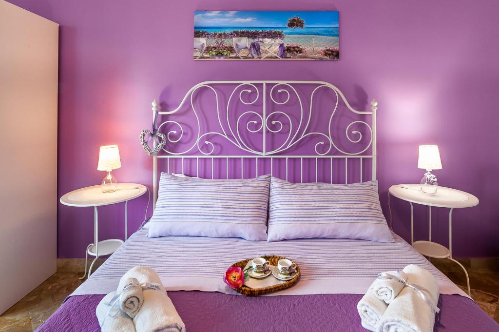 ein lila Schlafzimmer mit einem Bett mit Schuhen drauf in der Unterkunft Le stanze di Irma in Palermo