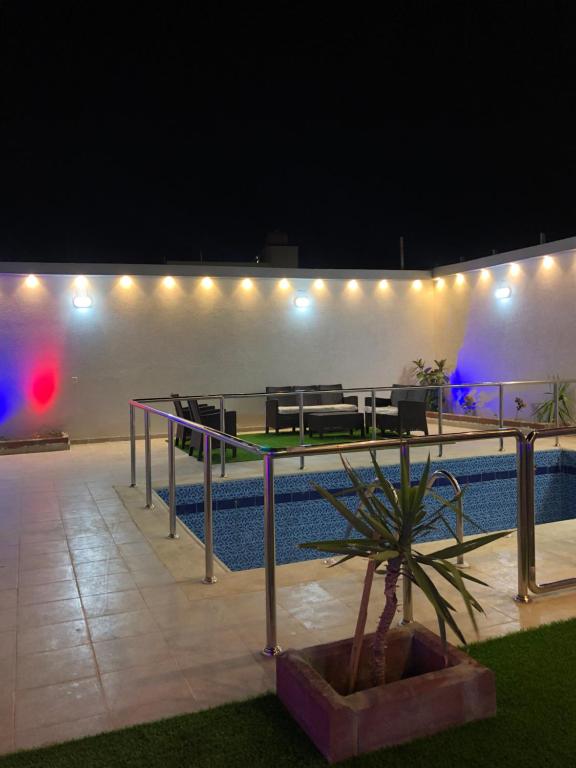 um pátio com uma mesa e cadeiras ao lado de uma piscina à noite em شاليه الماسة em Taif