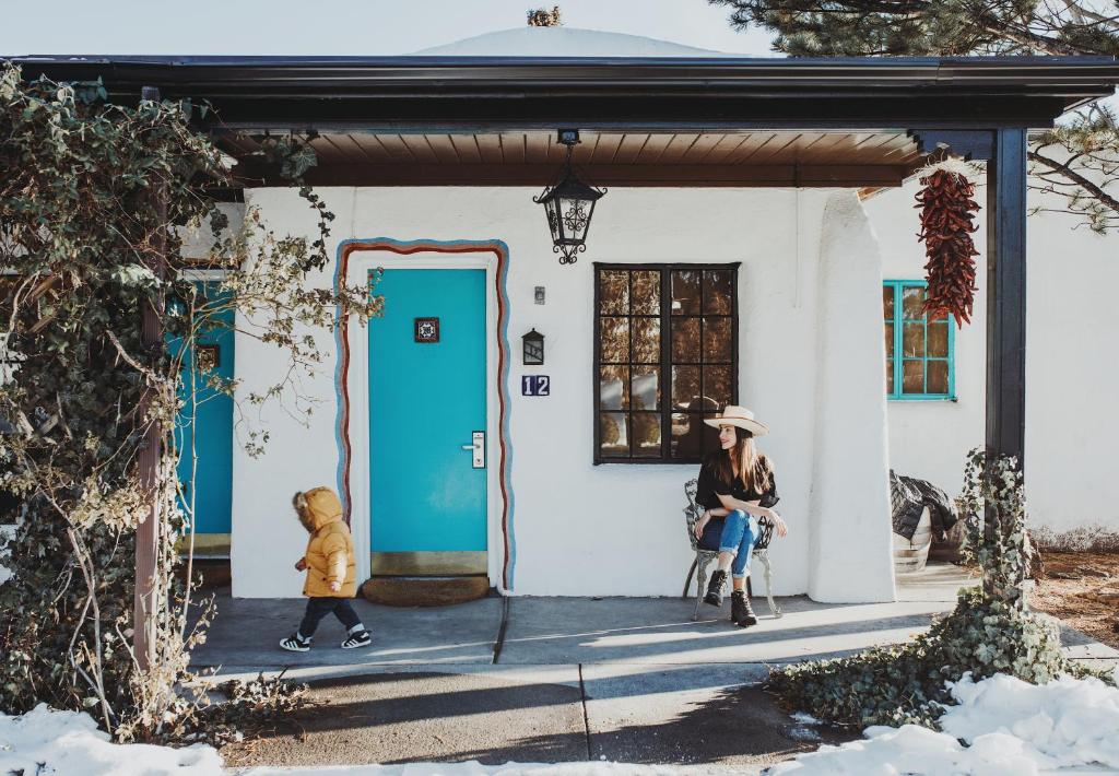 a woman sitting in a chair in front of a house at El Rey Court in Santa Fe