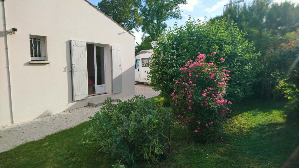 una casa blanca con un arbusto con flores rosas en Les Lavatères, en Hiers-Brouage