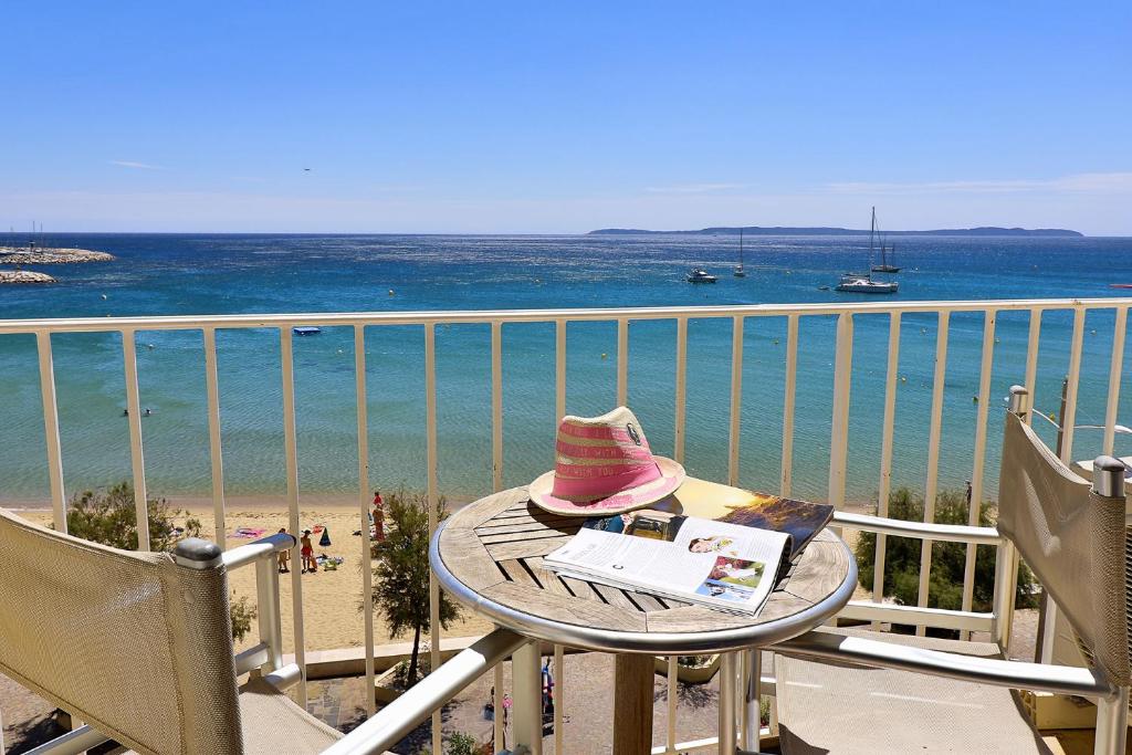 a hat sitting on a table on a balcony overlooking the beach at Hôtel Beau Rivage in Le Lavandou