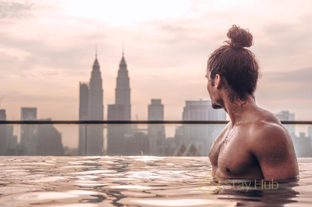 eine Frau in einem Infinity-Pool mit Stadtblick in der Unterkunft Regalia Residence The Sky Pool Suite in Kuala Lumpur