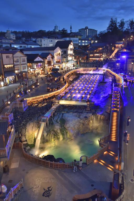 a view of a city at night with a pool at Kusatsu Onsen Hotel Village in Kusatsu