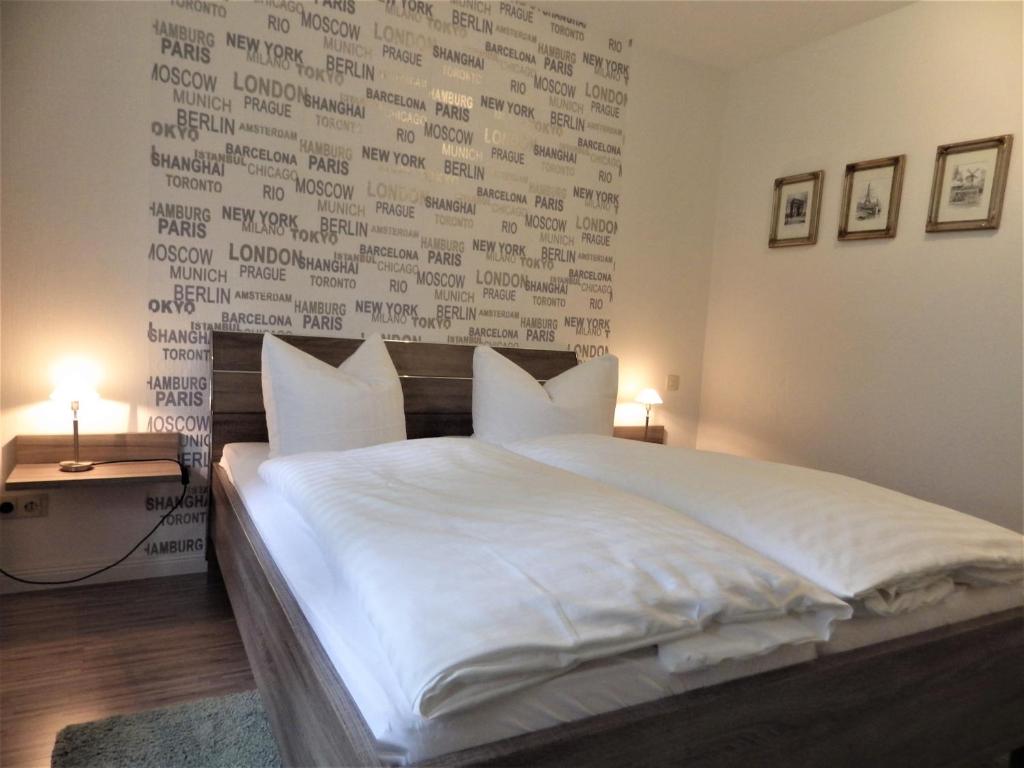 a bedroom with a large white bed with aritten wall at Pension Haus Heitzig in Lippstadt