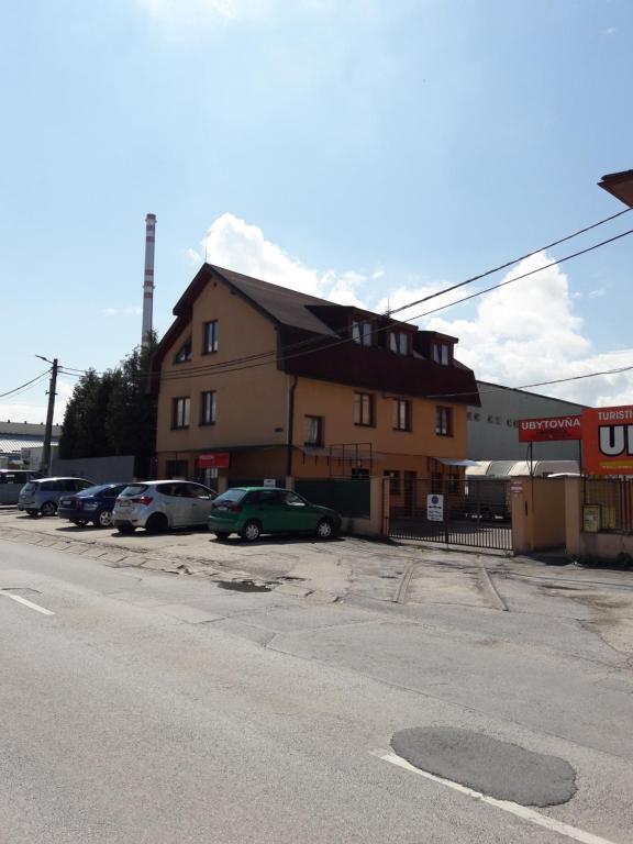 a building with cars parked in a parking lot at Ubytovňa Tavros in Žilina