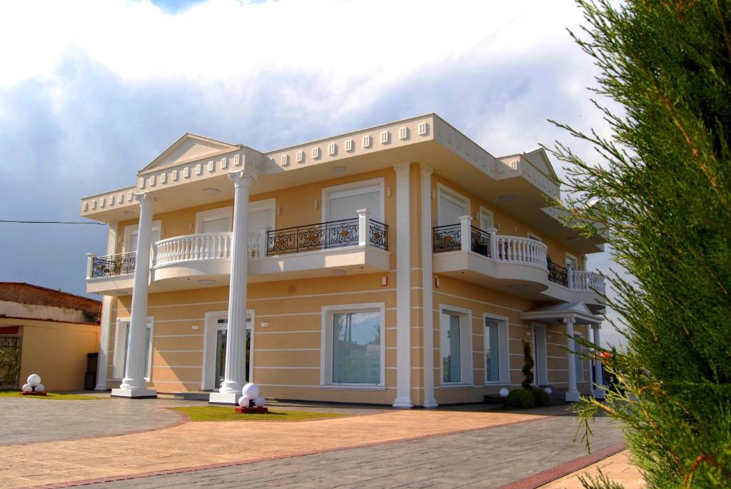uma grande casa amarela com uma varanda em Villa Elena em Kateríni
