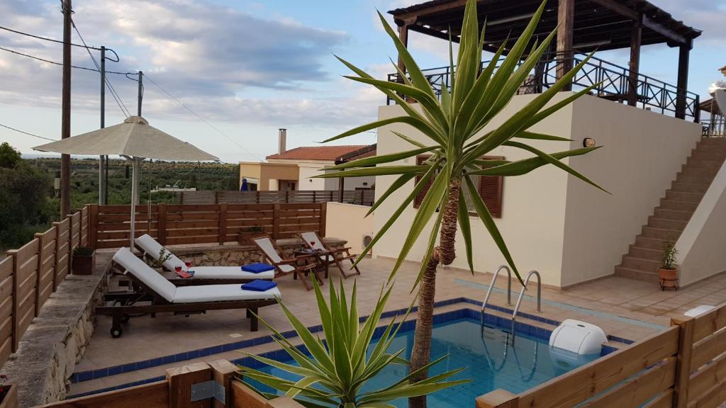 un patio con una palmera y una piscina en Sharon's Stone Villa, en Rethymno